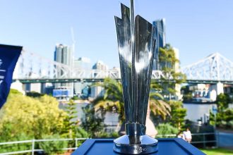 ICC Men’s T20 World Cup trophy on display outdoors with city skyline.