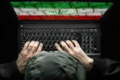 Hands typing on a laptop with an Iran-flag graphic on the screen, representing cyber hacking activity.
