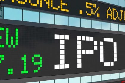 Close-up of a stock exchange-style electronic display with the word “IPO” in large white block letters, surrounded by green and yellow ticker text and numbers on black screens.