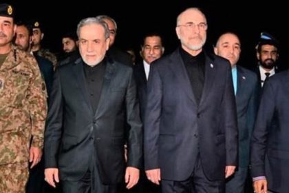 Group of officials walking together at night, including a Pakistani army officer and members of an Iranian delegation in formal attire.