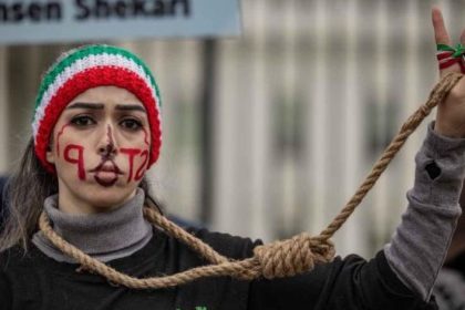 A protester with face paint and an Iranian-colored headband raises a peace sign while wearing a rope around the neck during an anti-execution demonstration.