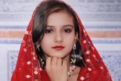 Portrait of Khalida, 22, from Khairpur, Sindh, wearing a red traditional dupatta and earrings.