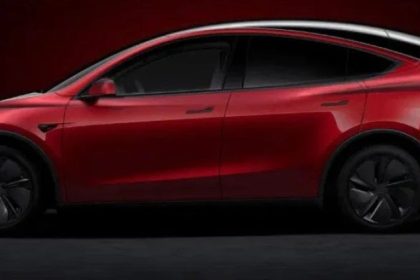 A red Tesla Model Y electric SUV appears in side view against a dark background.