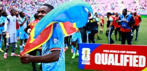 DR Congo player Cedric Bakambu celebrates with the national flag after qualifying for the FIFA World Cup.