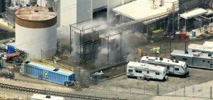 An aerial view shows smoke or vapor near a large storage tank at an industrial facility in Garden Grove.