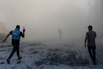 A journalist runs with others toward the scene of an explosion after an Israeli strike on the outskirts of Gaza City.