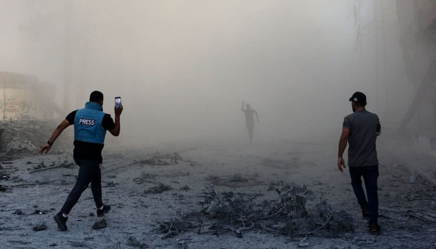A journalist runs with others toward the scene of an explosion after an Israeli strike on the outskirts of Gaza City.