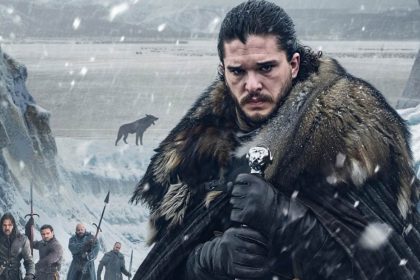 Jon Snow from HBO’s Game of Thrones wearing a heavy fur cloak and holding a sword amid falling snow.