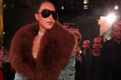 Kim Kardashian attends the Gucci 2027 Cruise Collection show in New York City in a heavily layered outfit, oversized black sunglasses, and a brown fur-style collar.