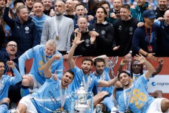 Manchester City players and coaching staff celebrate with the FA Cup trophy after beating Chelsea in the final.