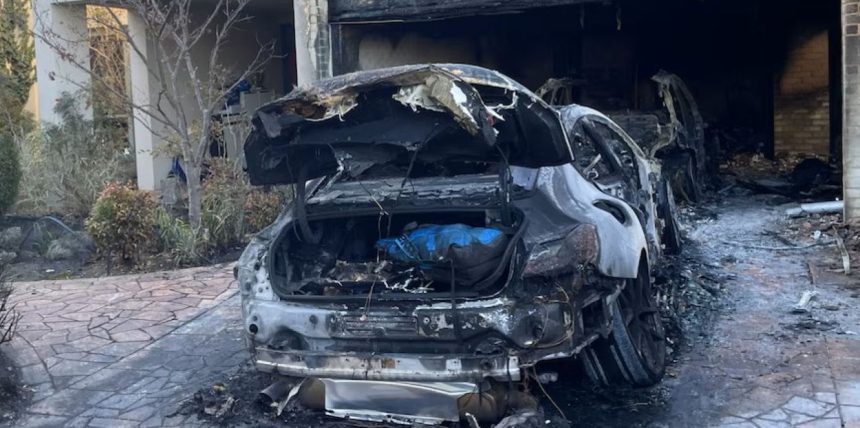A severely burned car sits in a driveway outside a fire-damaged building following a reported arson incident in Melbourne.