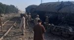 Security personnel and civilians stand beside damaged railcars and train tracks after a blast near Chaman Phatak in Quetta.