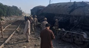 Security personnel and civilians stand beside damaged railcars and train tracks after a blast near Chaman Phatak in Quetta.