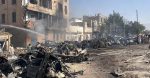 Burned vehicles, damaged buildings, smoke and fire hoses are visible after an explosion near Chaman Phatak in Quetta.
