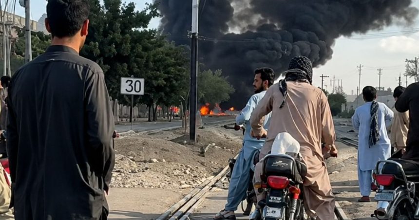 People on motorcycles watch thick black smoke rising near a railway track after a reported train blast near Chaman Phatak in Quetta.