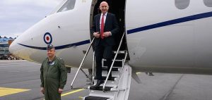 ALT Text: Defence Secretary John Healey stands on the steps of an aircraft during a visit to Estonia, with a uniformed officer nearby.