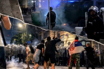 Protesters face a line of riot police with shields during smoky nighttime clashes in Belgrade, Serbia.
