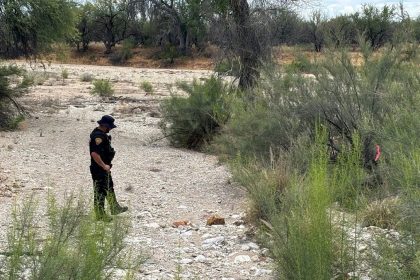 A Tucson police officer stands in a dry riverbed where human remains were found during a search for Nancy Guthrie.