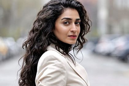 Actress Hajra Yamin poses in a light-colored blazer on a city street.