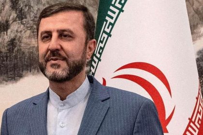 Iranian Deputy Foreign Minister Kazem Gharibabadi standing in front of an Iranian flag.