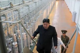 Kim Jong Un walks inside a uranium enrichment facility with industrial equipment and officials nearby on Sptember 13, 2024.