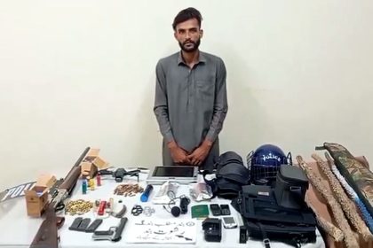 Shahid Aslam, an employee of Mehran Arshad Khawaja, stands near items recovered by law enforcement agencies during a raid in Mirpur, Azad Jammu and Kashmir.