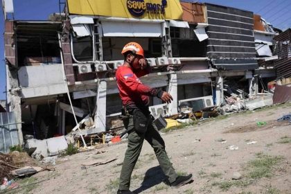 Rescue worker walks past a damaged building after an earthquake in General Santos, Philippines.