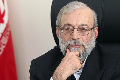 Mohammad-Javad Ardashir Larijani seated beside an Iranian flag.