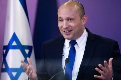Naftali Bennett speaks at a press conference at the Knesset in Jerusalem, with an Israeli flag behind him.