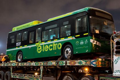 Green electric bus transported on a truck after Narowal electric buses arrived under Punjab government directives.