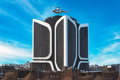 Cancer hospital building in Tehran with a helicopter flying above it under a clear blue sky.