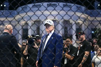 Donald Trump attends a White House UFC event behind a cage fence.
