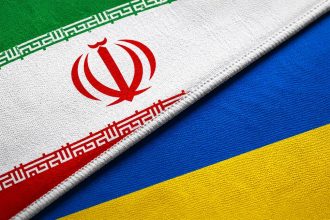 Close-up of the national flags of Iran and Ukraine displayed side by side with detailed fabric textures.