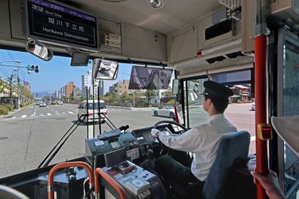 A bus driver operates a public bus in Japan, representing Japan’s transport sector and driver workforce.