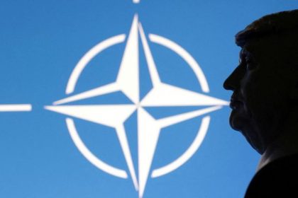 US President Donald Trump silhouette beside NATO emblem
