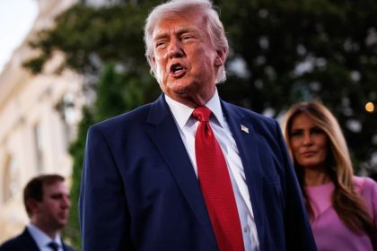 Donald Trump speaking with Melania Trump in the background.