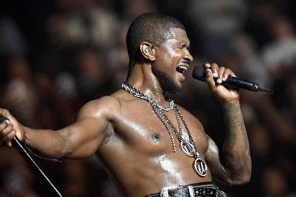 Usher singing passionately on stage during a live concert while holding a microphone. Image: Getty Images.