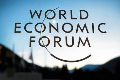 World Economic Forum logo on glass with a blurred Davos background.