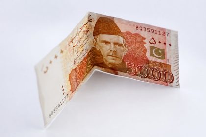 A Pakistani Rs5,000 currency note issued by the State Bank of Pakistan is displayed in a folded position