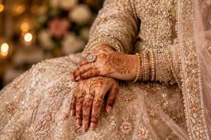 Bride’s henna-adorned hands with bangles on an embroidered wedding dress.
