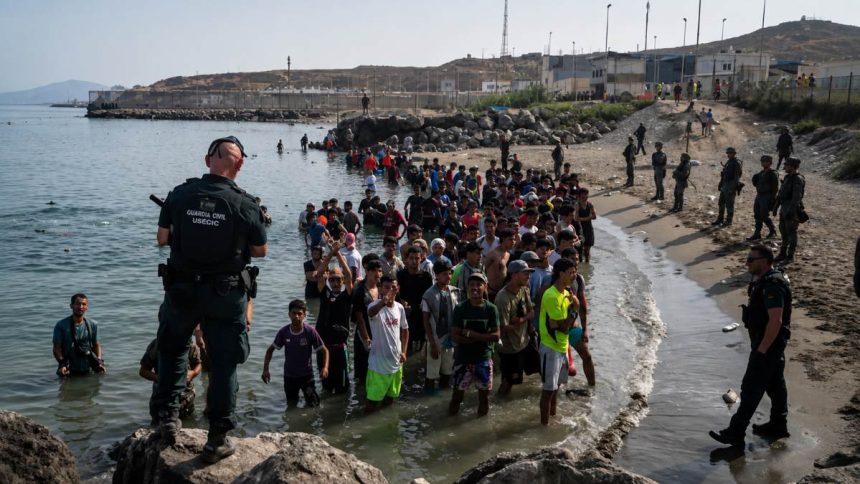 Spain’s Guardia Civil USECIC officers confront migrants on Tarajal Beach in Ceuta after they crossed from Morocco on July 31, 2026. Image Credit: Adri Salido/Getty Images.