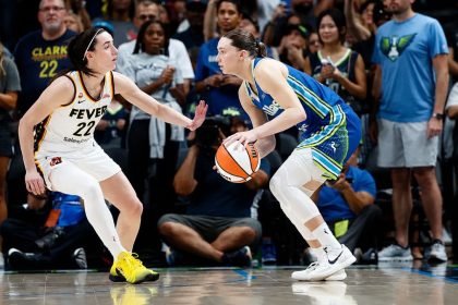Paige Bueckers controls the ball as Caitlin Clark defends
