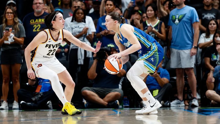 Paige Bueckers controls the ball as Caitlin Clark defends