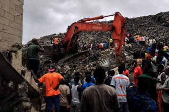 Guinea landfill collapse in Conakry as an excavator clears debris while people gather at the site