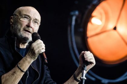 English singer, drummer, and songwriter Phil Collins performing on stage with a microphone during a live concert. Image Credit: indailysa