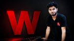 Wafflix founder Mir Ali Raza standing next to the Wafflix "W" logo at the company's office.