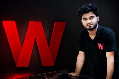 Wafflix founder Mir Ali Raza standing next to the Wafflix "W" logo at the company's office.