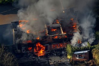 Building engulfed in flames during West Midlands wildfires.