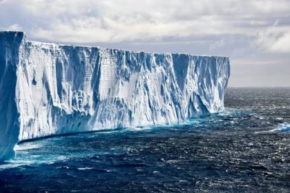 Massive Antarctic iceberg floating in the Southern Ocean beneath a cloudy sky.
