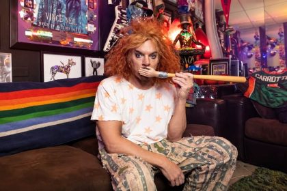 Comedian Carrot Top posing in a colorful room.